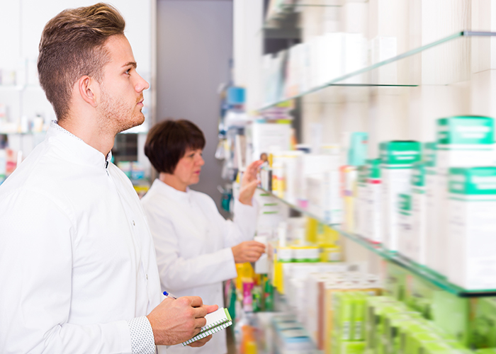 Male pharmacy technician checks the shelves for a medication.