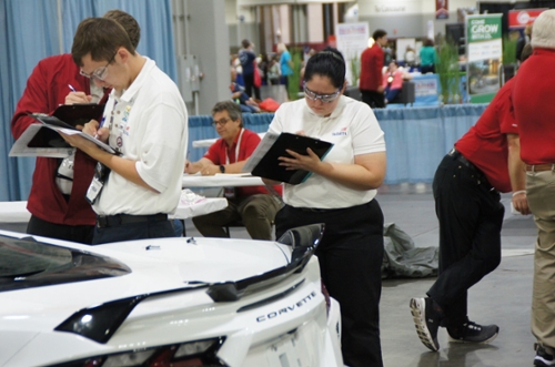 Lauren Lewis (center) evaluates a car for the collision damage appraisal category. 